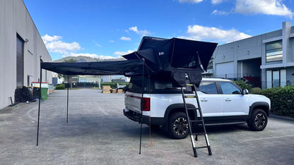 Nomad Camper ABS Hardshell Rooftop Tent | Low-Profile Design.
White truck with a large black rooftop tent in an outdoor setting. 